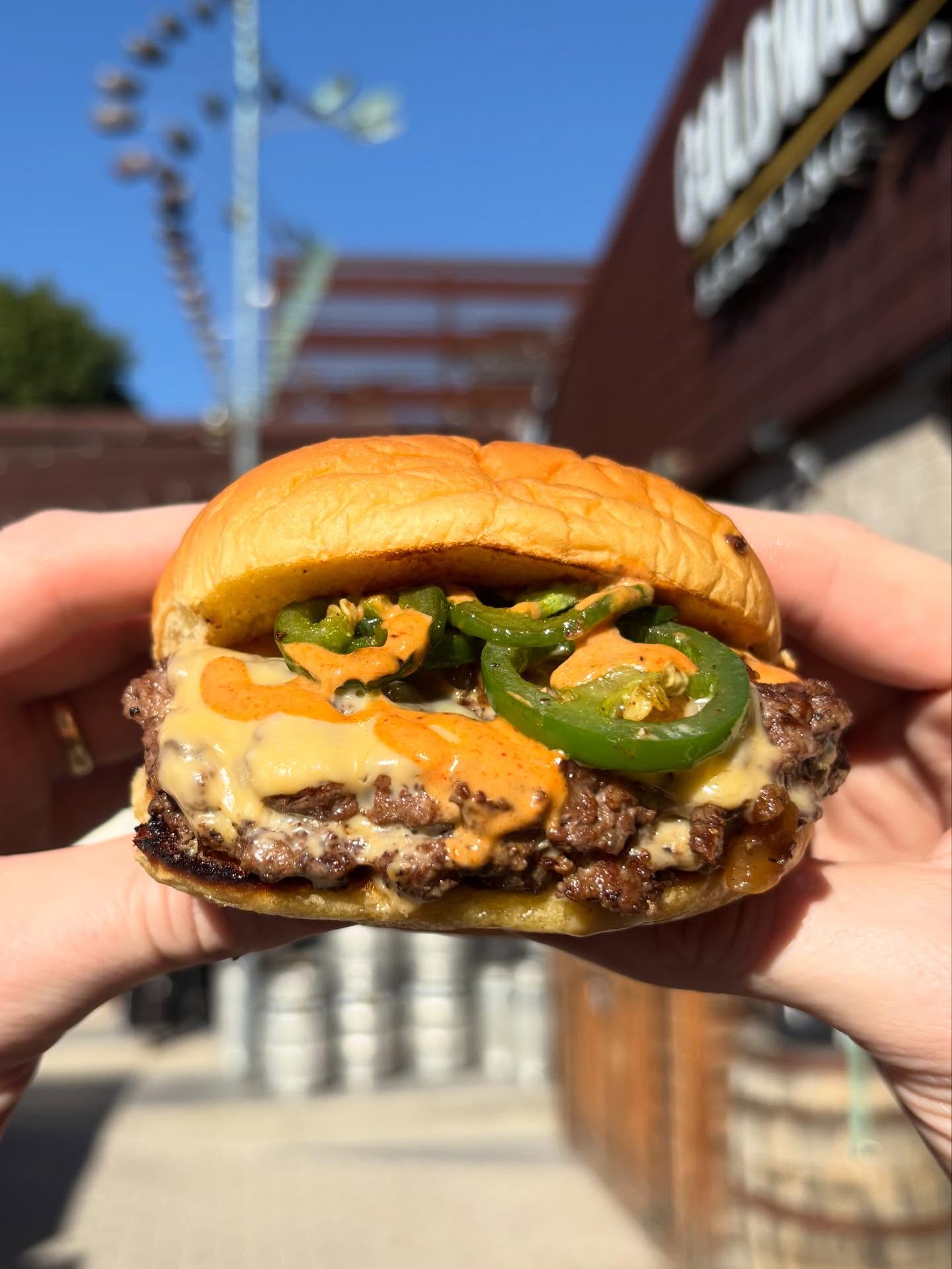 Grass-fed smash burger with grilled jalapeños, melted cheese, and spicy sauce